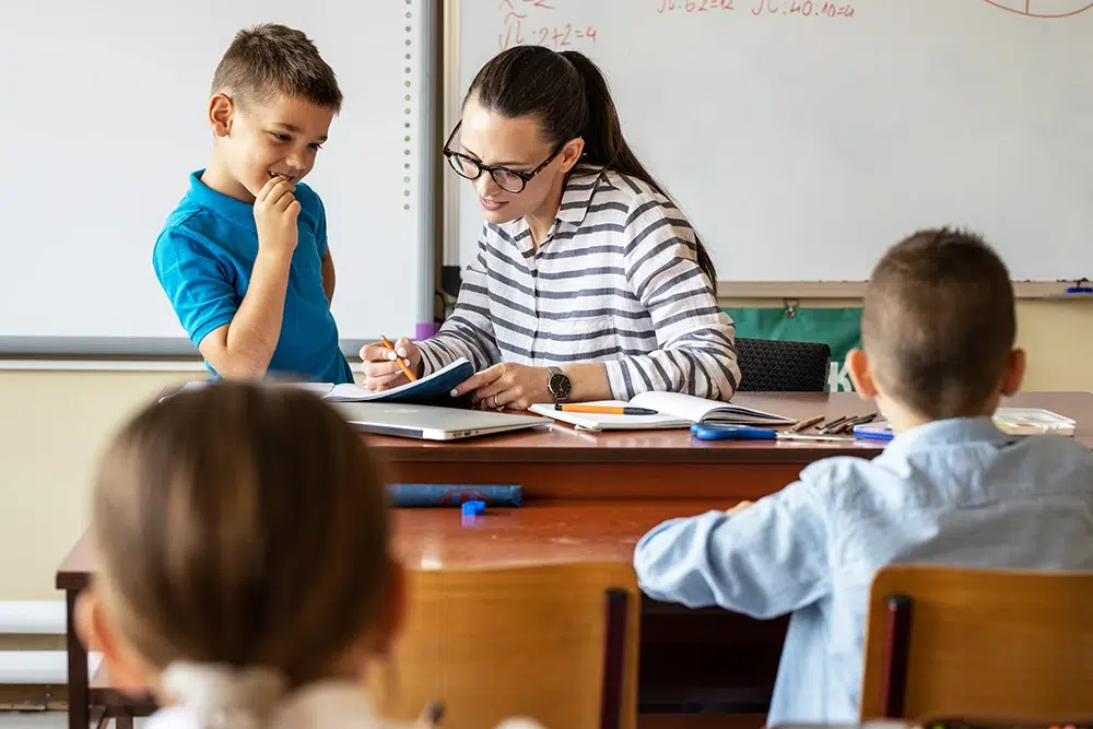 idee-on-freiwillige-ganztagsschule-betreuung Betreuerin hilft Kindern in der Ganztagsschule bei den Hausaufgaben