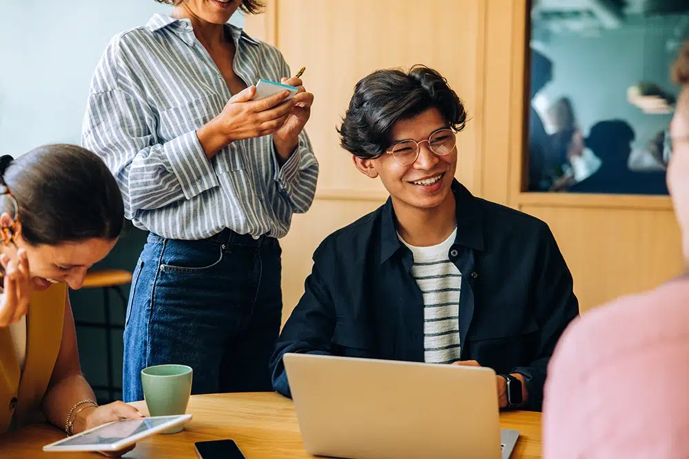 Junge Menschen im Gespräch am Tisch mit Laptop