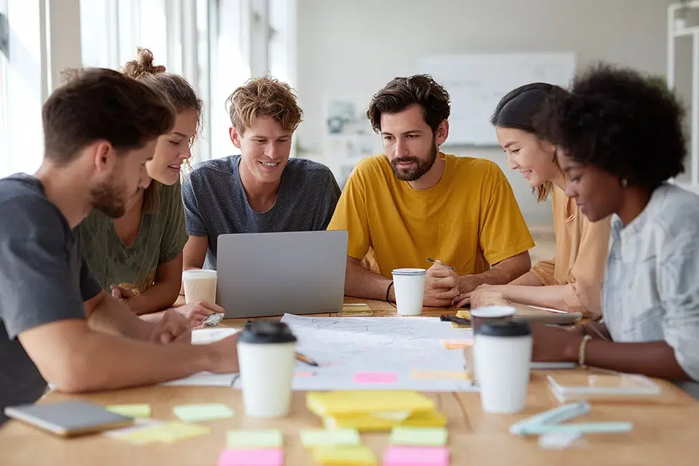 idee-on-gruppe-junger-leute-in-meeting Team bespricht sich gemeinsam am Tisch