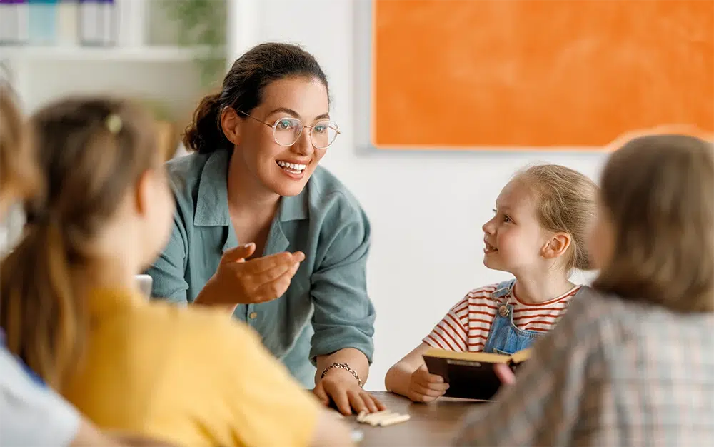 Betreuerin spielt fröhlich mit Kindern am Tisch
